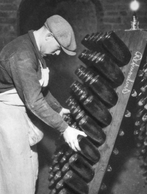 A worker attending to bottles undergoing secondary, in-bottle, fermentation during the Méthode Champenoise. 